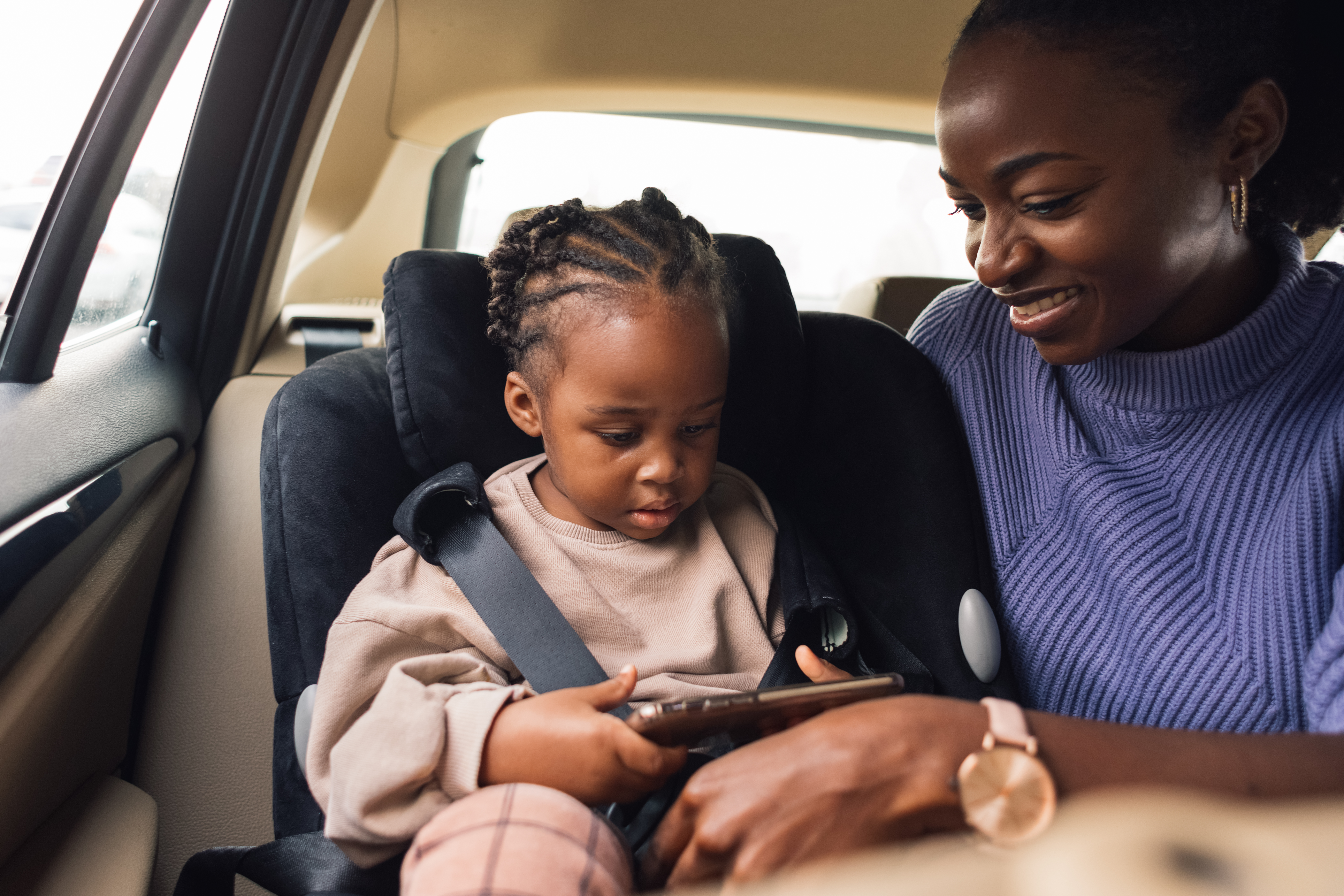 Kvinna och barn i bil som tittar på en mobil
