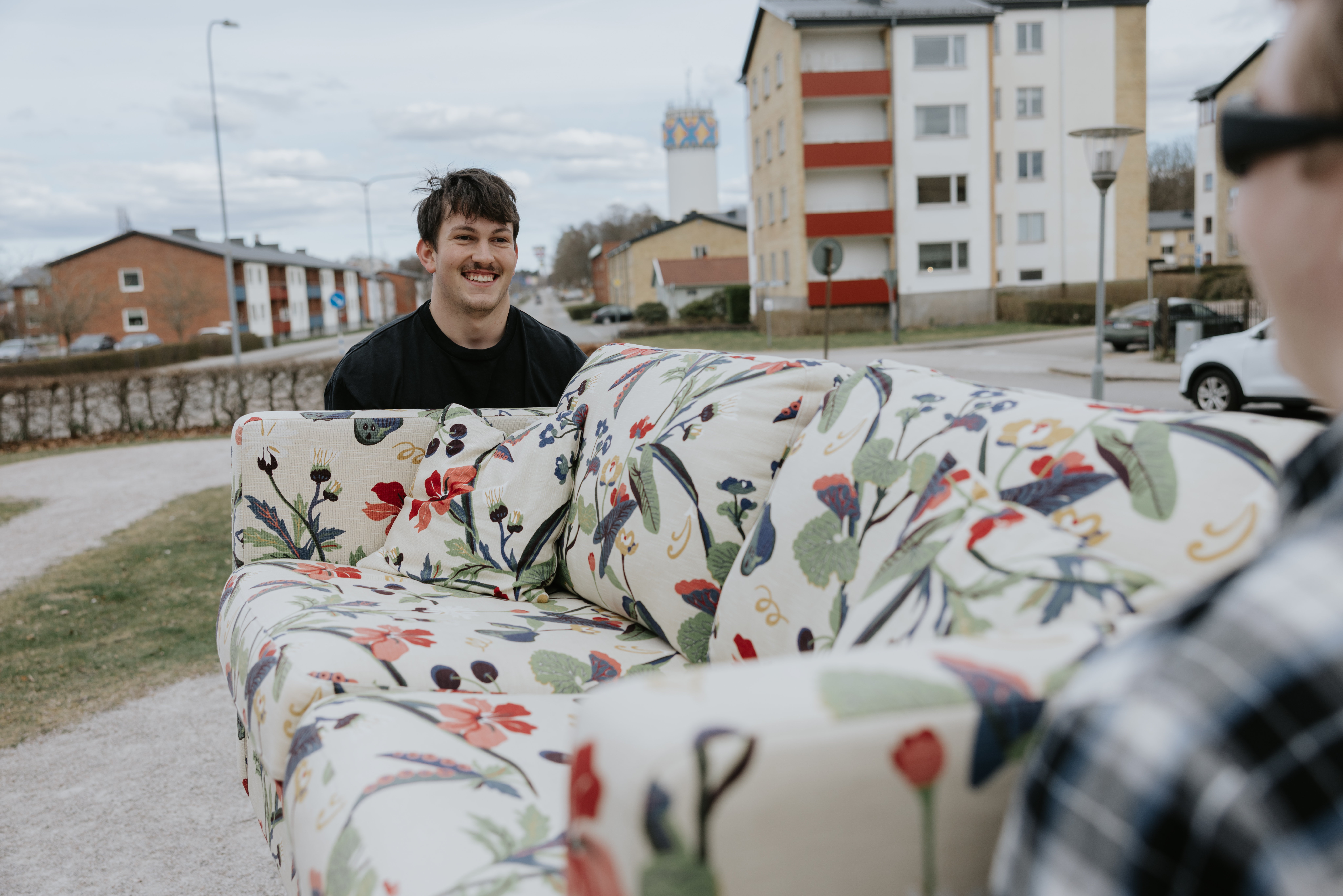 Två unga vuxna bär en soffa