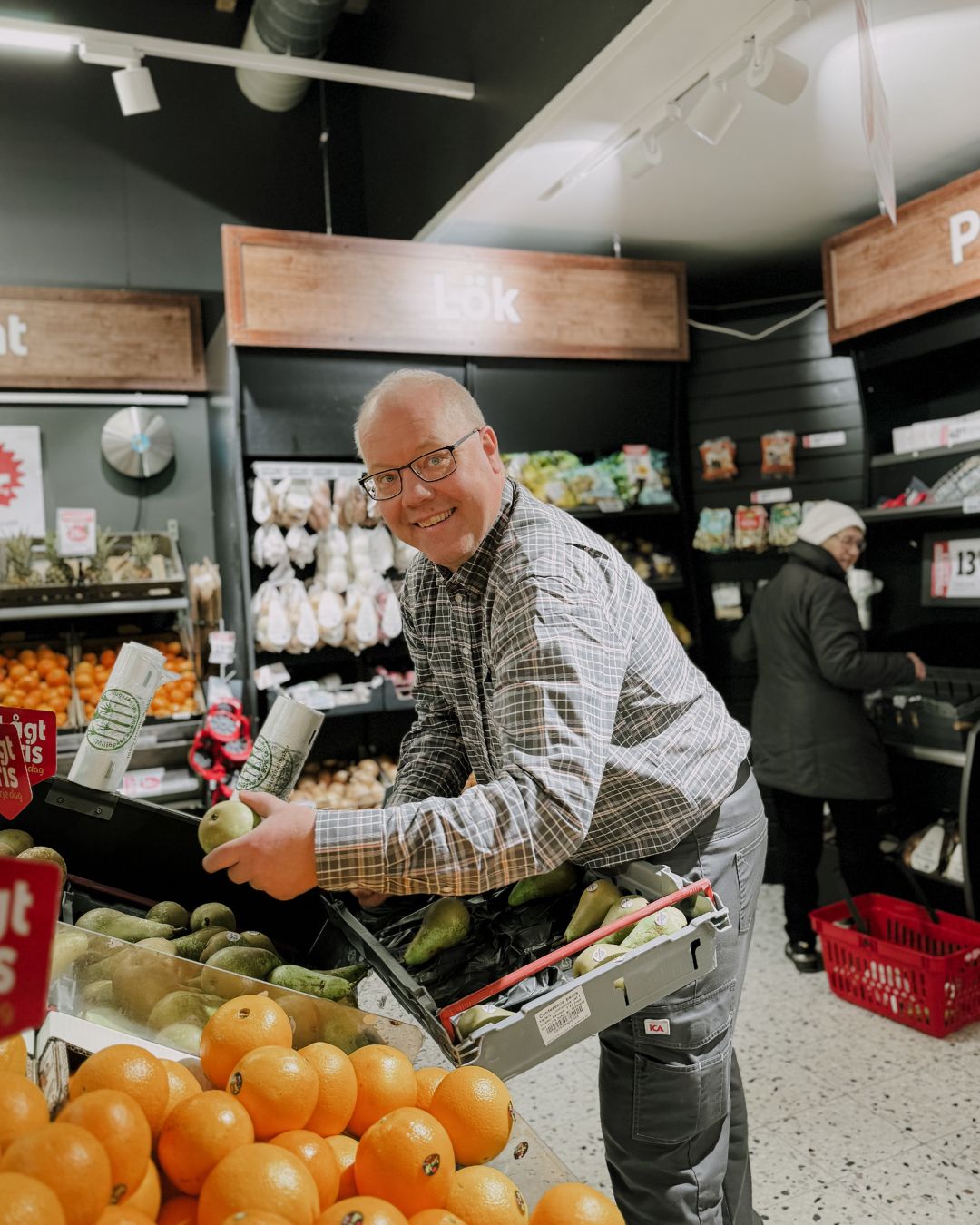 Jonas fyller på päron i frukthyllorna